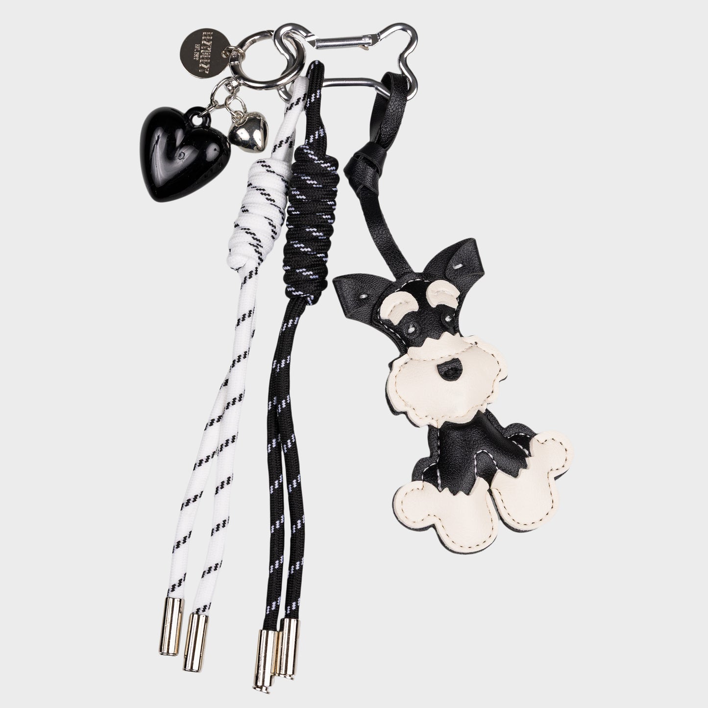 Musta valkoinen snautseri laukkukoriste, missä on lisänä musta sydän koriste ja kaksi roikkuvaa nauhaa